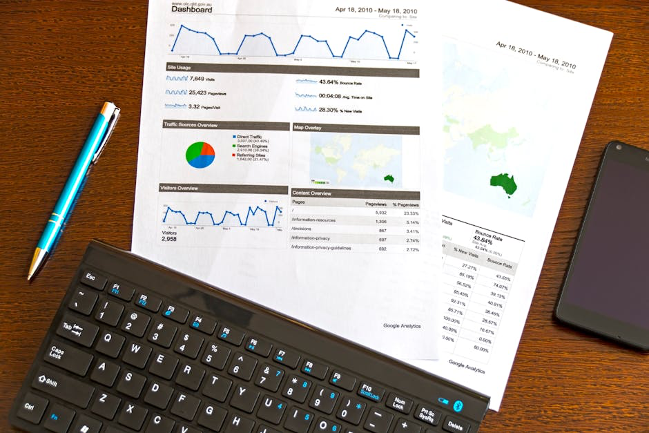 Printed analytics reports with charts and graphs on a desk beside a keyboard, pen, and smartphone