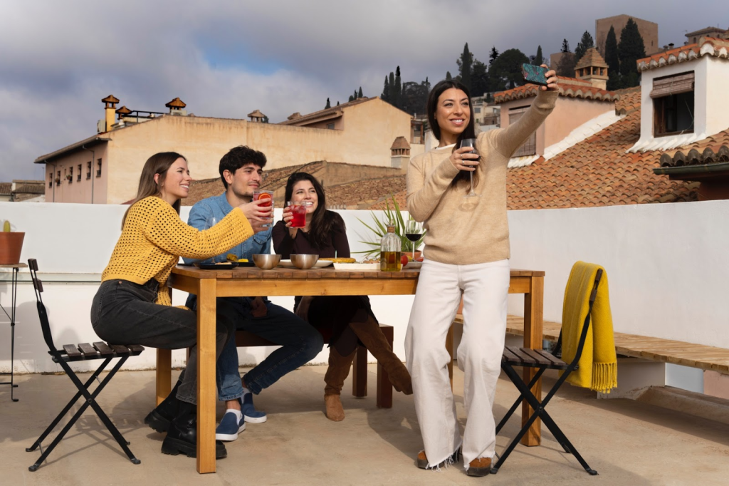 Friends taking a group selfie while enjoying drinks outdoors