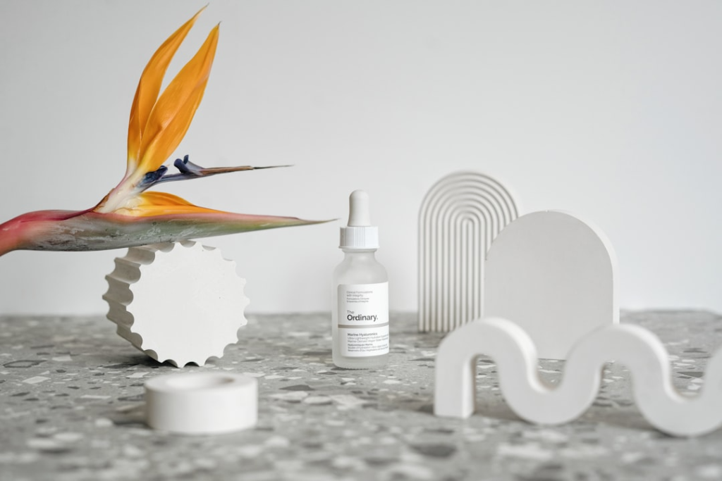 Flat lay featuring a CPG beauty product alongside other lifestyle items - CPG influencer marketing Skincare serum bottle styled with abstract white props and a bird of paradise flower