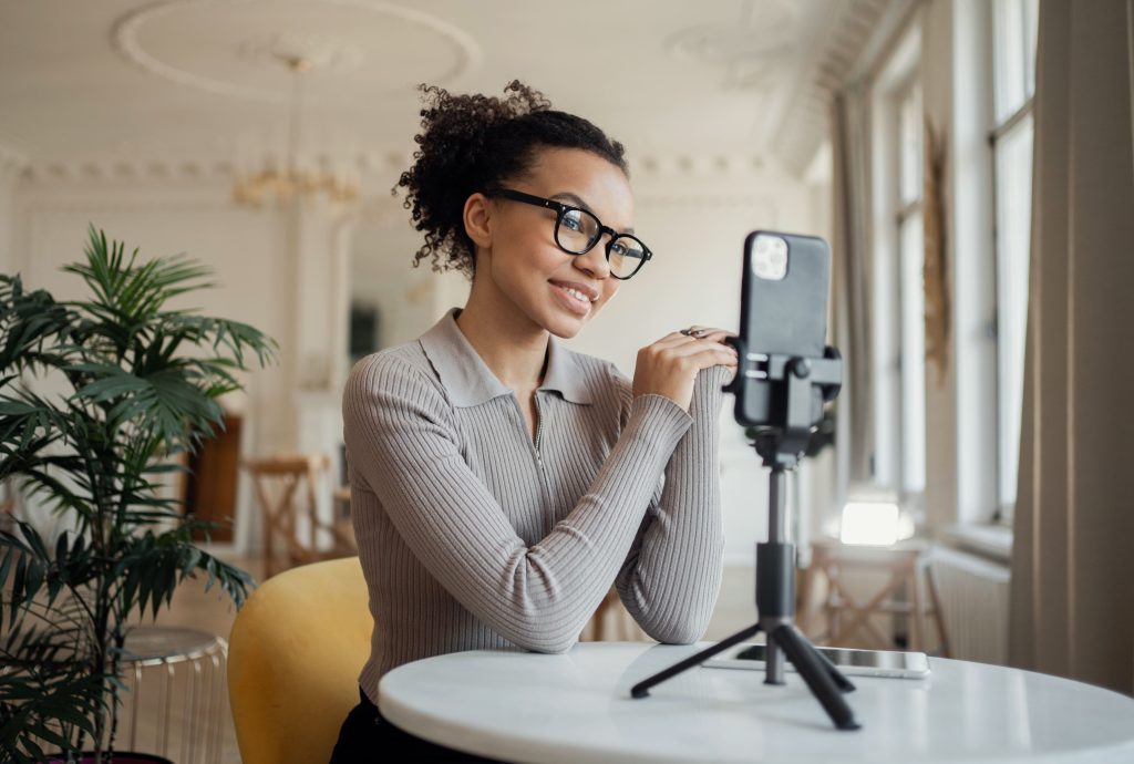 smiling woman with glasses filming blog